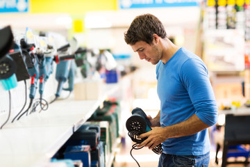 young man shopping for sander in hardware store