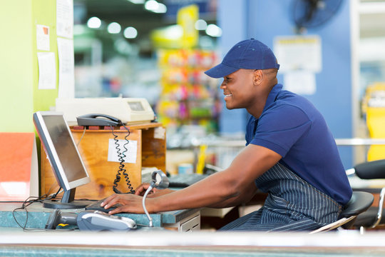 african male cashier working at till point