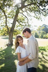 Fototapeta premium Smiling couple standing and embracing in park