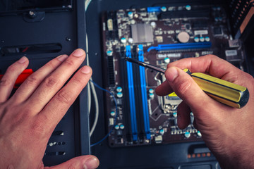 Hand with screwdriver installing computer