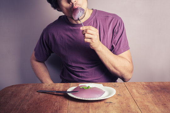 Young man eating purple pudding