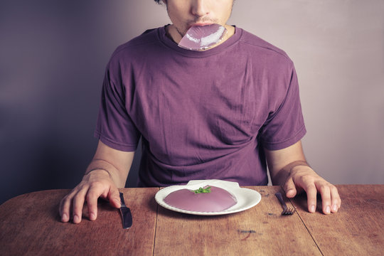 Young man eating purple pudding
