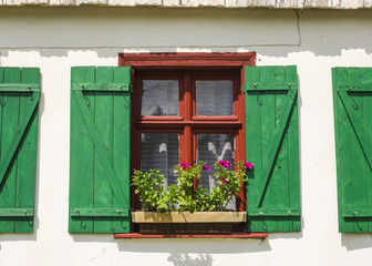Window with green shutters and flowers in wooden rural house