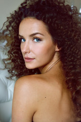 Portrait of a curly girl with blue eyes with bared shoulders
