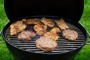succulent steaks and burgers cooking on a barbecue