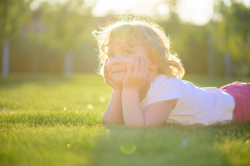 Fototapeta na wymiar Cute little girl lying in green grass