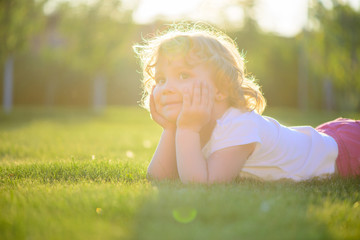 Cute little girl lying in green grass