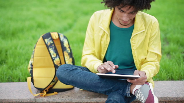 Young guy with original appearance enjoys tablet
