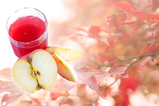 Apple juice and fresh apple on autumn background