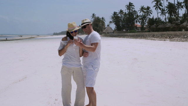 Couple taking photo on the beach, steadycam shot