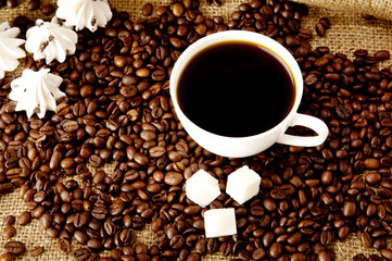 Cup of coffee with refined sugar and coffee beans