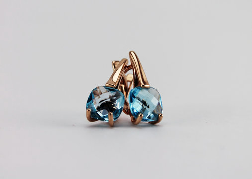 Jewelry. Gold earrings with blue Topaz. Isolated object on white