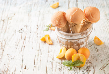 Apricot fresh ice cream scoops in cones on wood
