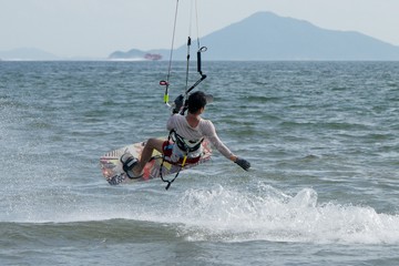 Male kite surfer jumping with ferry behind
