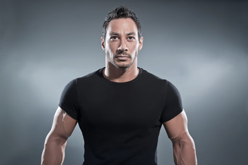 Combat muscled fitness man wearing black shirt and pants. Studio