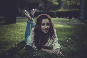 summer redhead girl with denim jacket lying on a park