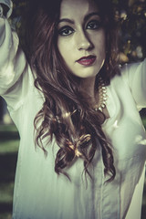 redhead girl with white shirt in a park with trees