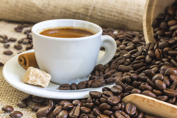 fresh espresso in white cup with lump sugar, cinnamon and roaste