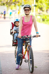 Obraz premium Caucasian young woman on a bicycle with little son behind