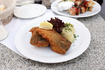 Fried carp with potatoes and slice of lemon