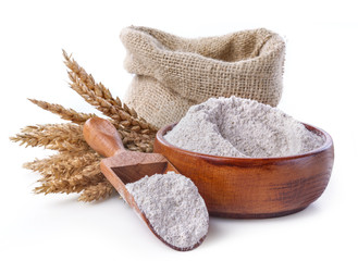 whole grain flour in a bowl and linen bag with a wooden spatula