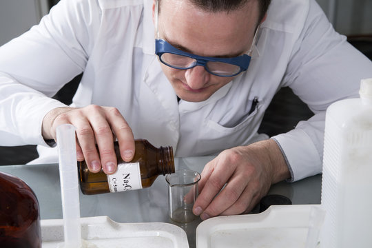 Laboratory assistant pours liquid from a bottle with sodium oxal