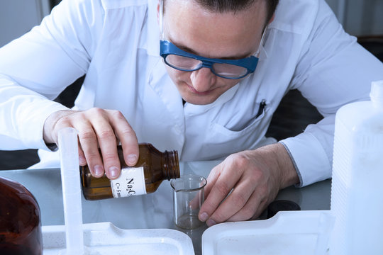 Laboratory assistant pours liquid from a bottle with sodium oxal