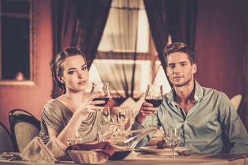 Young couple with glasses of wine in restaurant