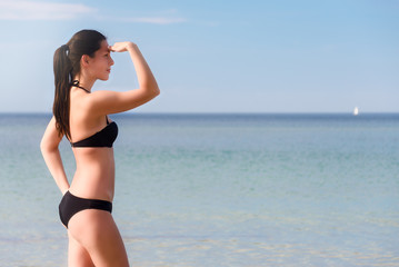 Fototapeta na wymiar Attraktive Frau im Bikini blickt aufs Meer