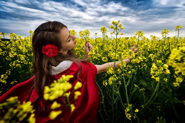 beautiful woman with red cloak  in yellow blooming field