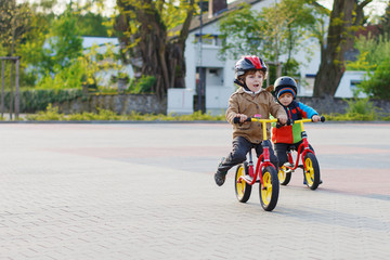Fototapeta premium Two little siblings having fun on bikes in city on vacations
