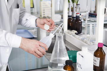 Laboratory assistant pours liquid from a bottle