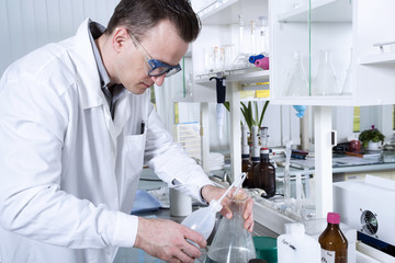 Laboratory assistant pours liquid from a flask
