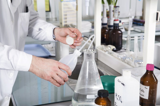 Laboratory assistant pours liquid from a bottle