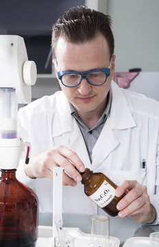 Laboratory assistant pours liquid from a bottle with sodium oxal