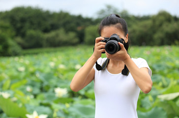 young woman photographer taking photo of blooming lotus at park 
