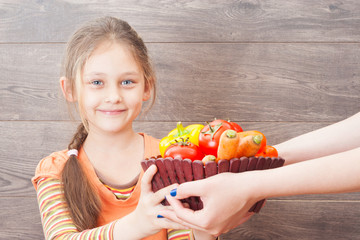 little girl takes hands basket with vegetables