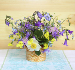Lovely bouquet of wild wildflowers is in a vase near the wooden