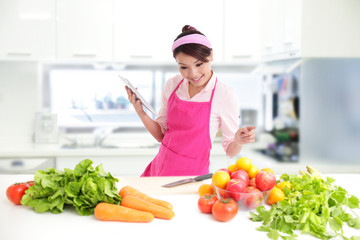 Young woman wearing kitchen apron with tablet