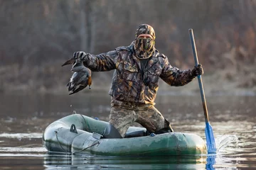 Photo sur Plexiglas Chasser hunter with dead duck in a boat