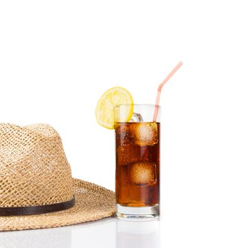 glass of fresh coke with straw near summer hat, summer time
