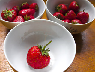Bowls of strawberries on wooden table