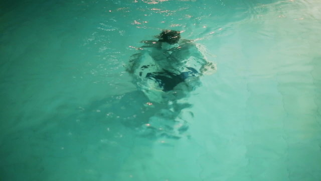Man sitting under water in swimming pool