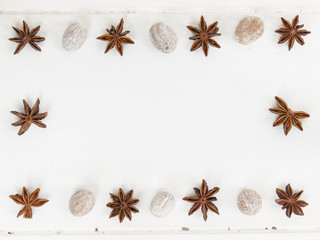 a frame of star anise and nutmeg on a rustic white table top