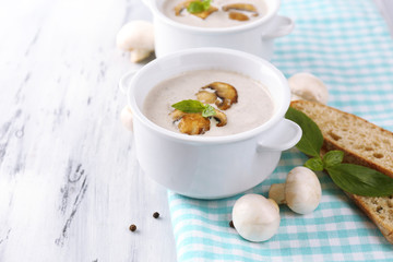 Mushroom soup in white pots, on napkin,  on wooden background
