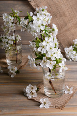 Beautiful fruit blossom in glass on table on grey background