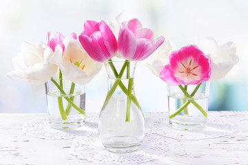 Beautiful tulips in bucket in vase on table on light background