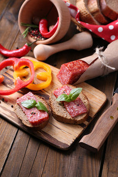 Composition with knife,  tasty sandwiches with salami sausage,