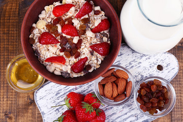 Healthy cereal with milk and strawberry on wooden table