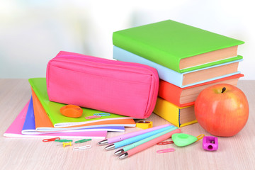 Bright school supplies on table on light background
